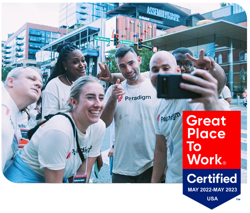 Paradigm team members taking a selfie, with the Great Place to Work Certified badge (May 2022–May 2023)