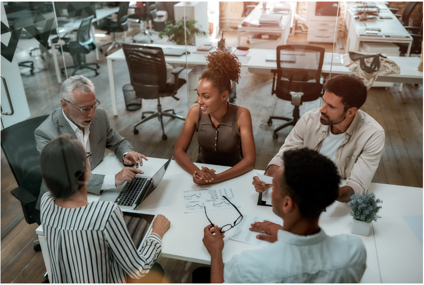 Colleagues meeting around a table with laptops